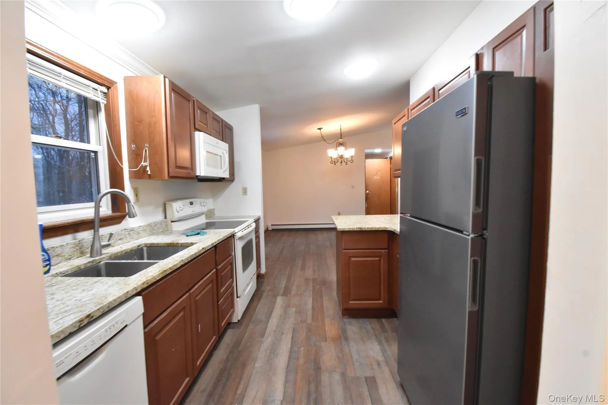 Kitchen featuring white appliances, light stone countertops, pendant lighting, a chandelier, and dark wood finished floors Kitchen featuring white appliances, light stone countertops, pendant lighting, a chandelier, and dark wood finished floors