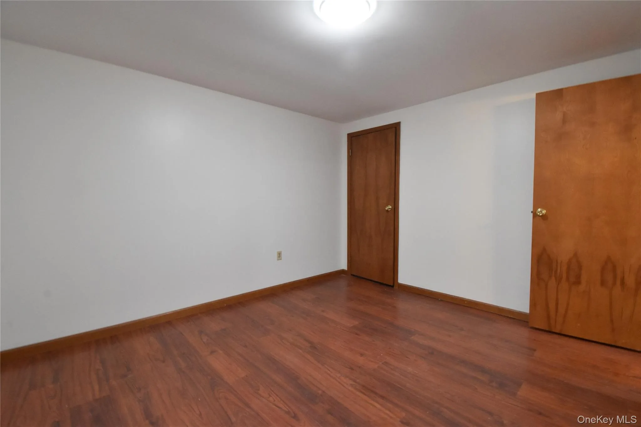 Spare room featuring baseboards and dark wood-style flooring Spare room featuring baseboards and dark wood-style flooring