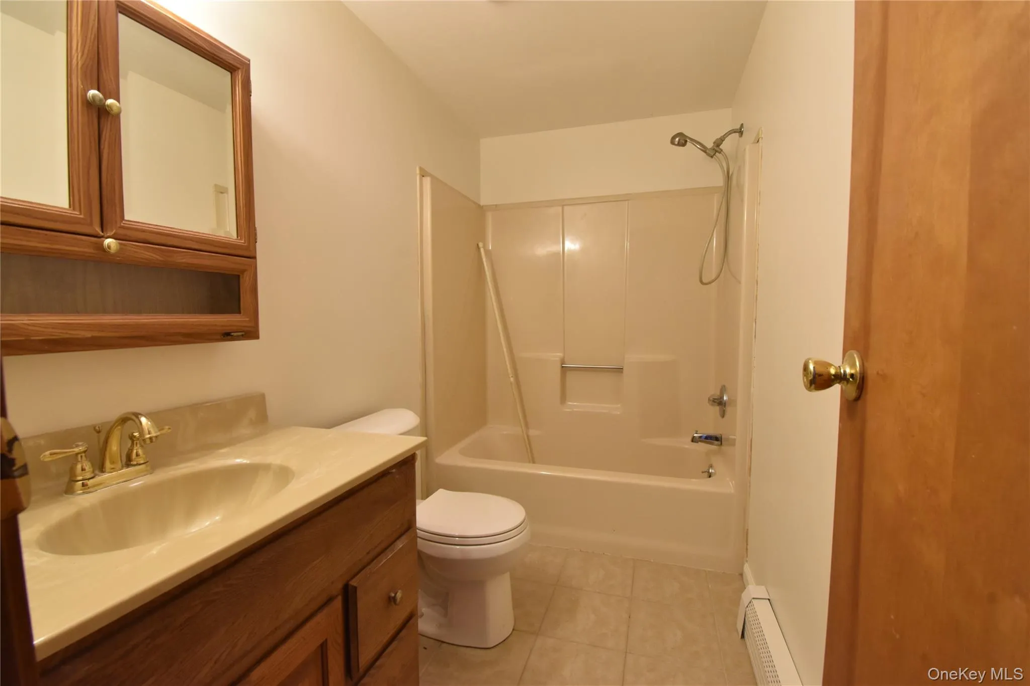 Full bathroom featuring vanity, bathing tub / shower combination, light tile patterned flooring, and a baseboard radiator Full bathroom featuring vanity, bathing tub / shower combination, light tile patterned flooring, and a baseboard radiator