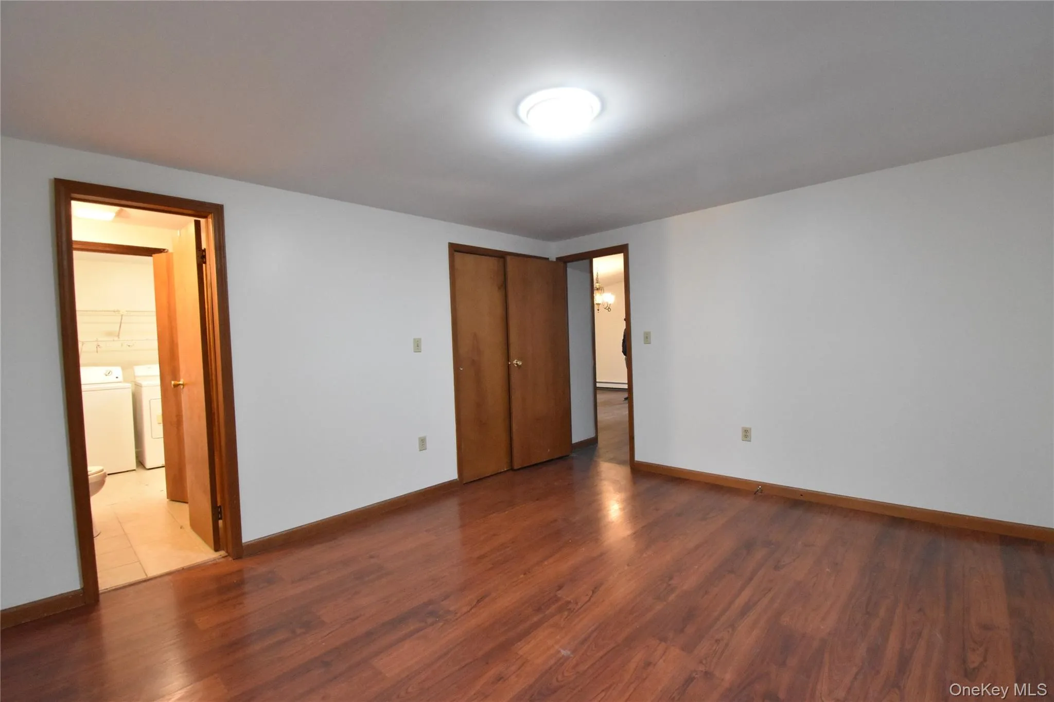Unfurnished bedroom with washer / clothes dryer, wood finished floors, and a closet Unfurnished bedroom with washer / clothes dryer, wood finished floors, and a closet