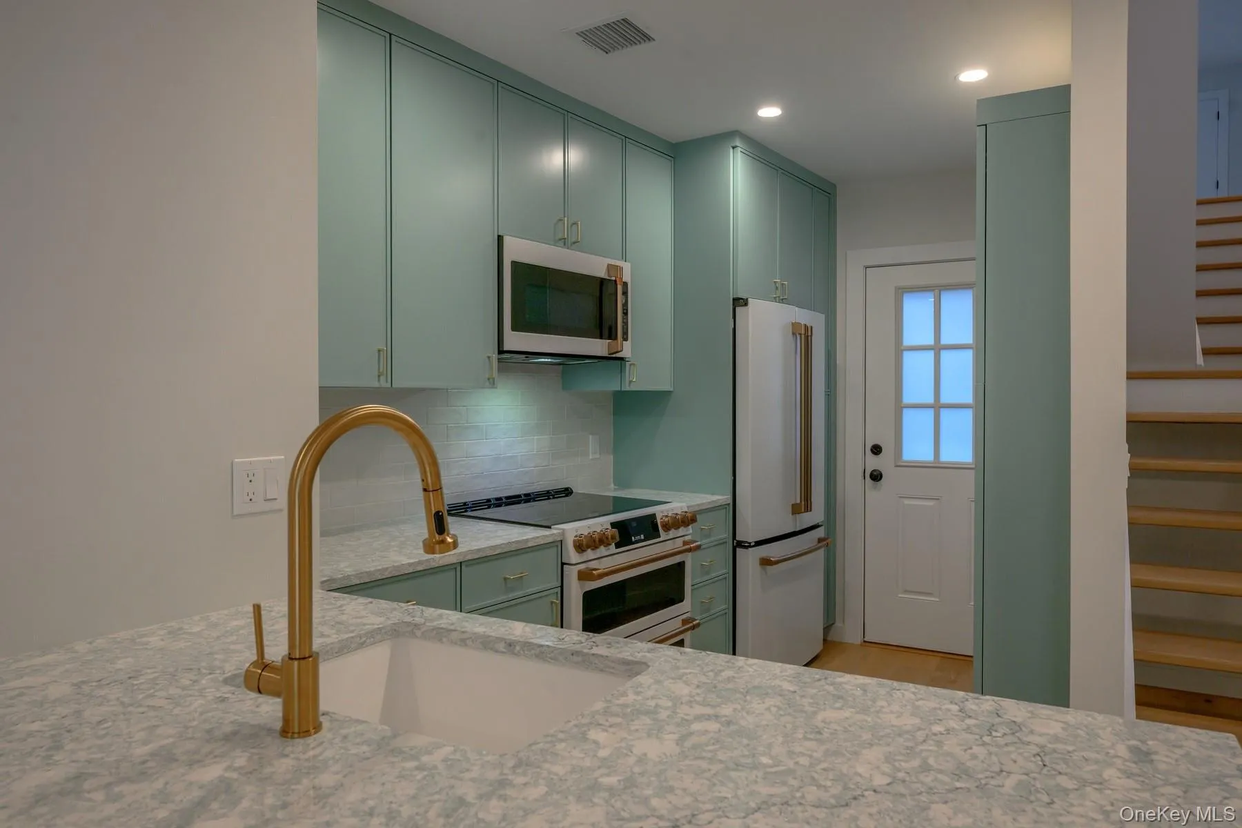 Kitchen with green cabinetry, white appliances, light stone counters, tasteful backsplash, and recessed lighting Kitchen with green cabinetry, white appliances, light stone counters, tasteful backsplash, and recessed lighting