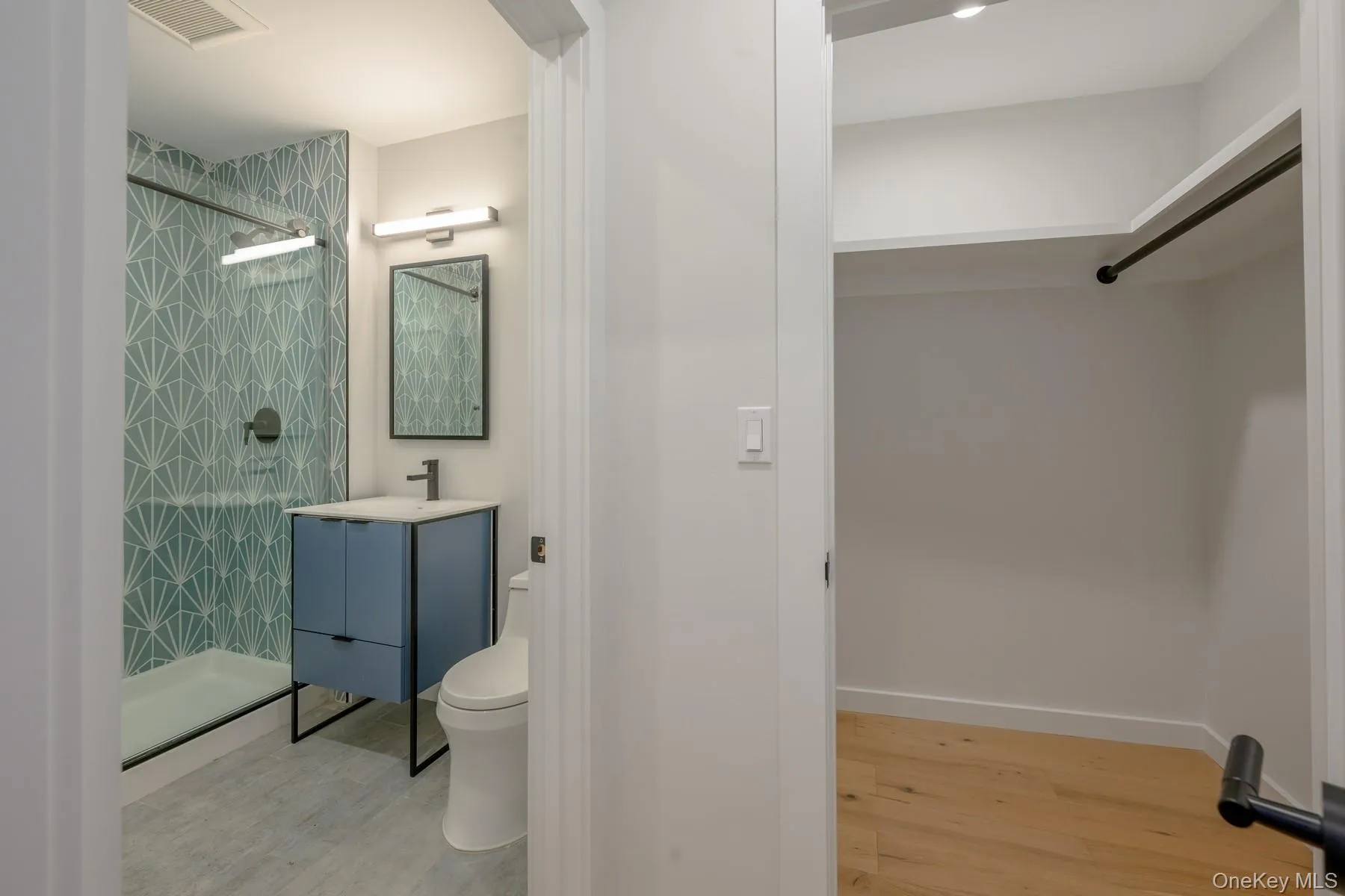 Bathroom featuring light wood finished floors, vanity, and a shower stall Bathroom featuring light wood finished floors, vanity, and a shower stall