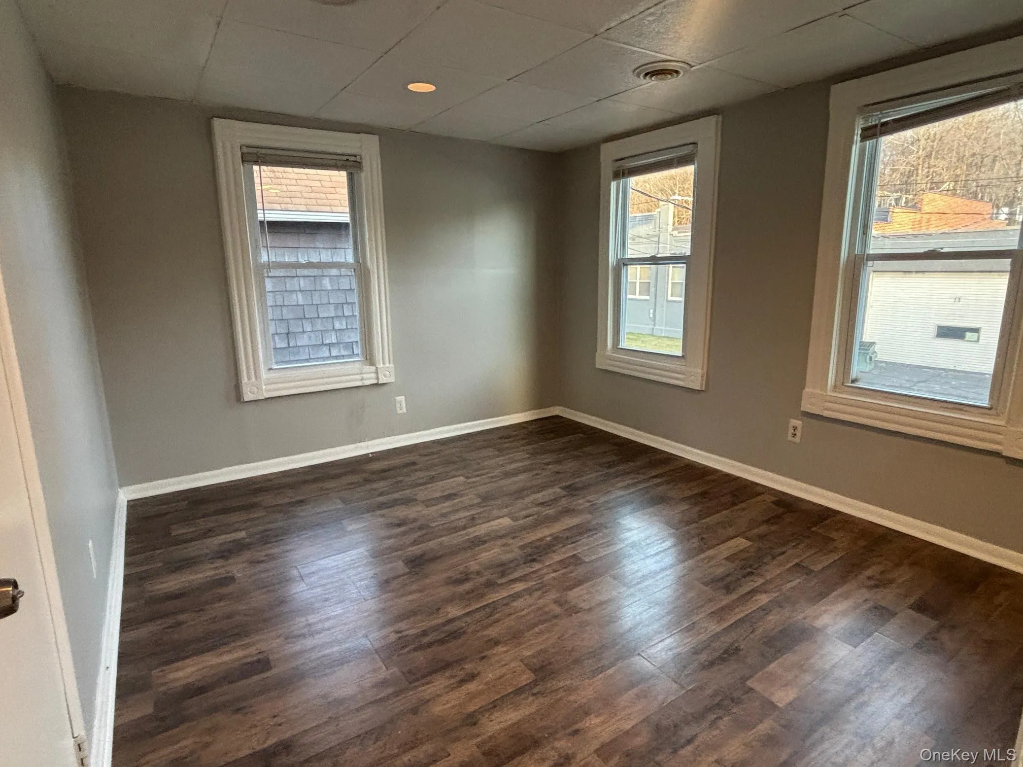 Empty room featuring a drop ceiling and dark wood-type flooring Empty room featuring a drop ceiling and dark wood-type flooring
