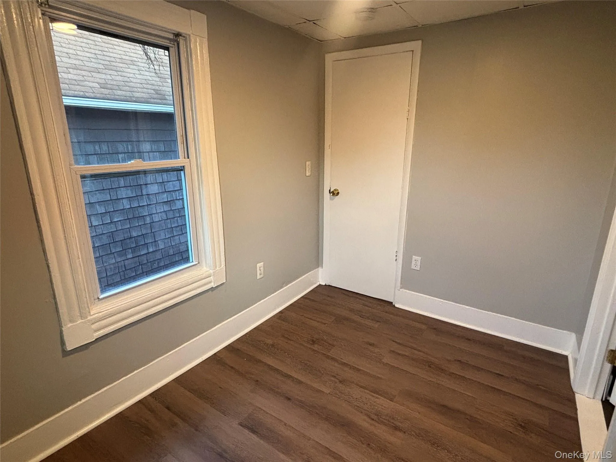 Empty room featuring dark wood-style flooring and a paneled ceiling Empty room featuring dark wood-style flooring and a paneled ceiling