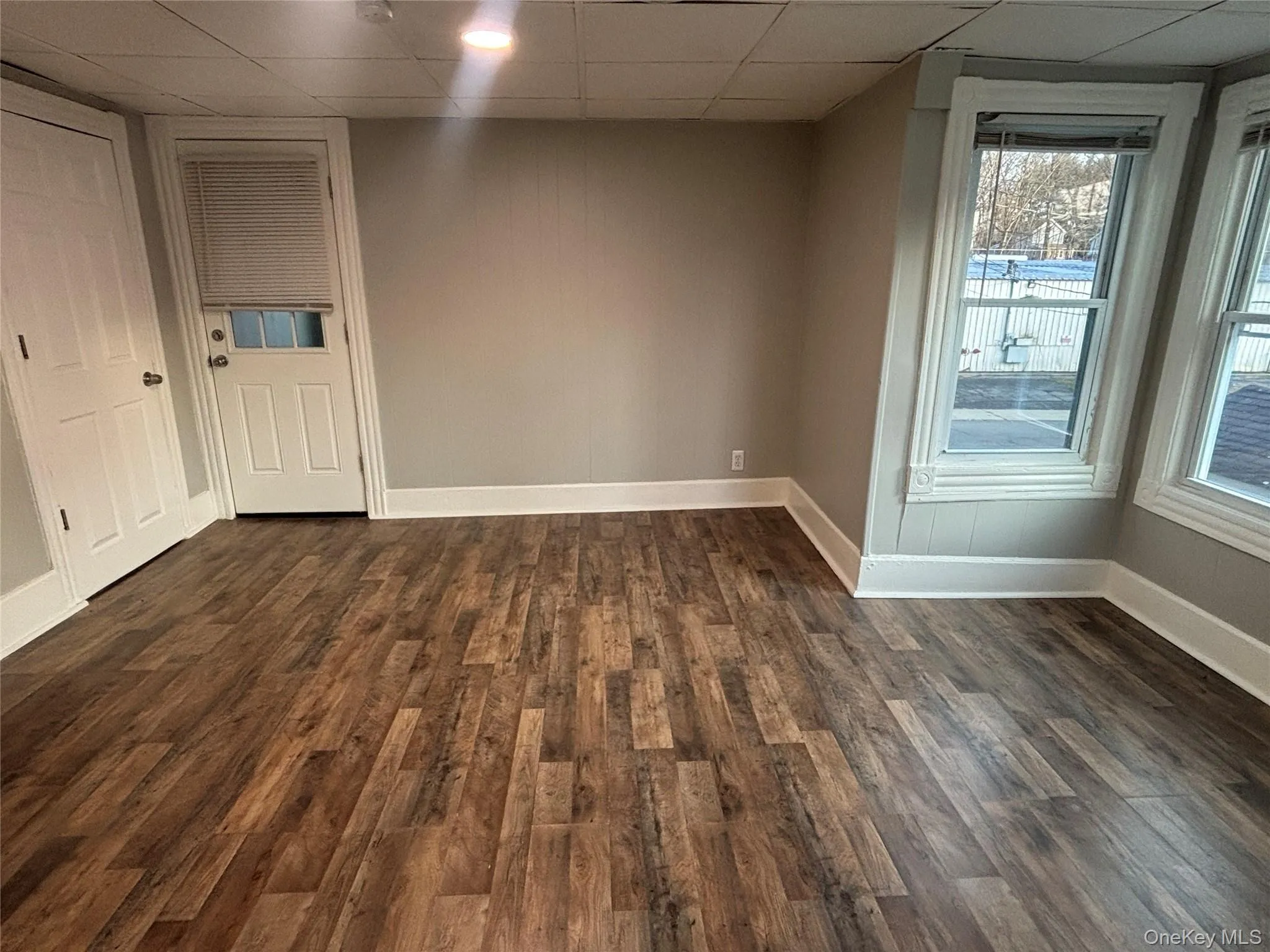 Spare room featuring dark wood-style floors and a drop ceiling Spare room featuring dark wood-style floors and a drop ceiling