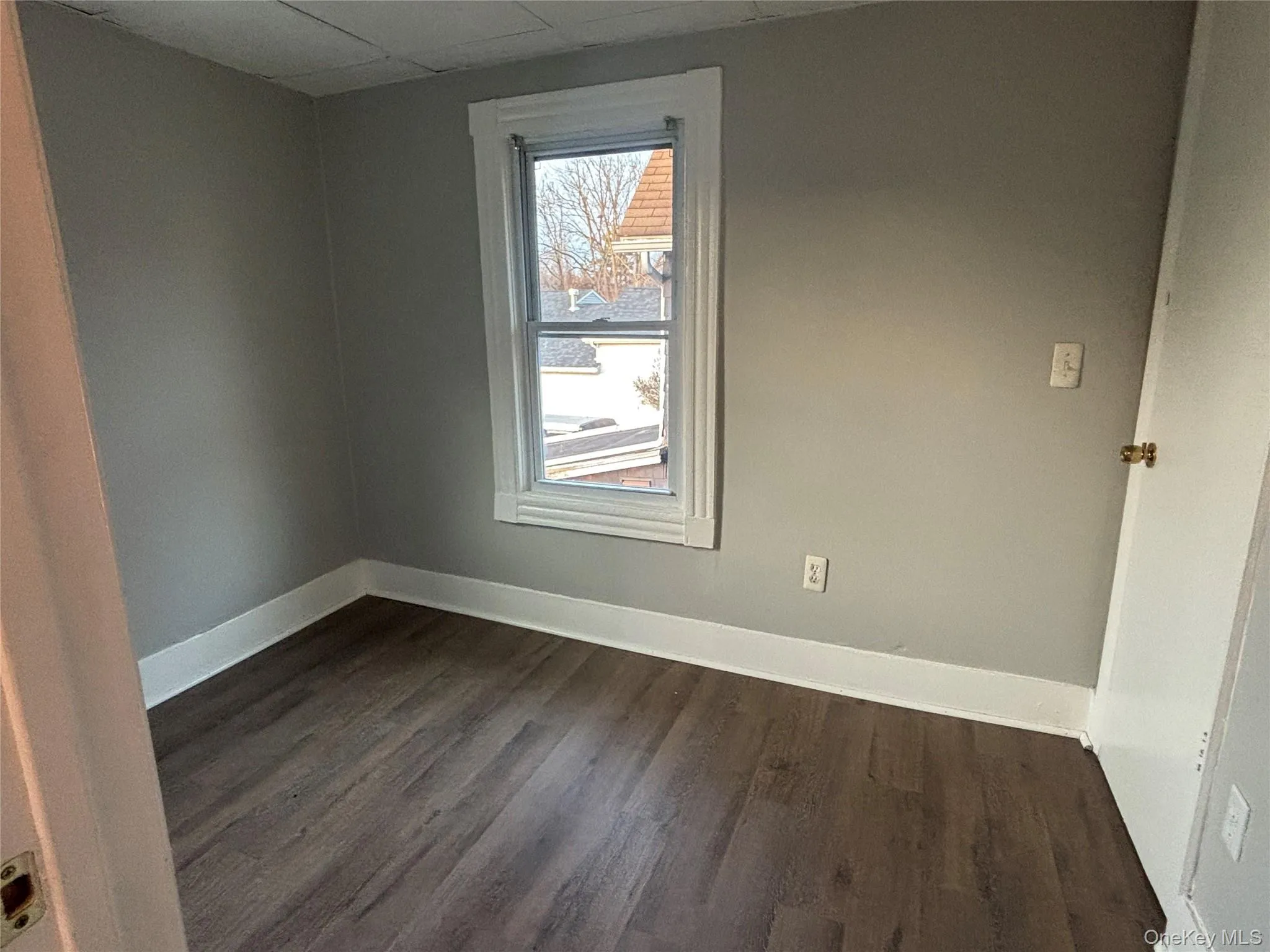 Spare room with dark wood-style flooring and a drop ceiling Spare room with dark wood-style flooring and a drop ceiling