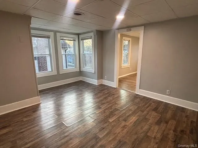 Unfurnished room featuring a drop ceiling and dark wood-style flooring Unfurnished room featuring a drop ceiling and dark wood-style flooring