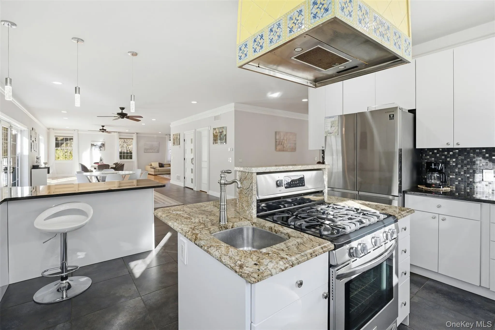 Kitchen with appliances with stainless steel finishes, extractor fan, open floor plan, a center island with sink, and white cabinetry Kitchen with appliances with stainless steel finishes, extractor fan, open floor plan, a center island with sink, and white cabinetry