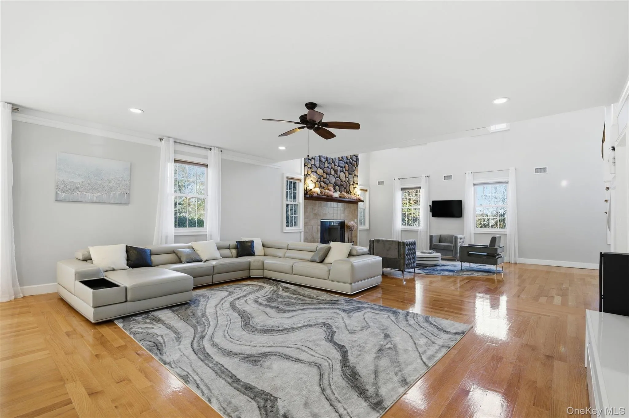 Living area featuring plenty of natural light, recessed lighting, ceiling fan, a fireplace, and hardwood / wood-style flooring Living area featuring plenty of natural light, recessed lighting, ceiling fan, a fireplace, and hardwood / wood-style flooring