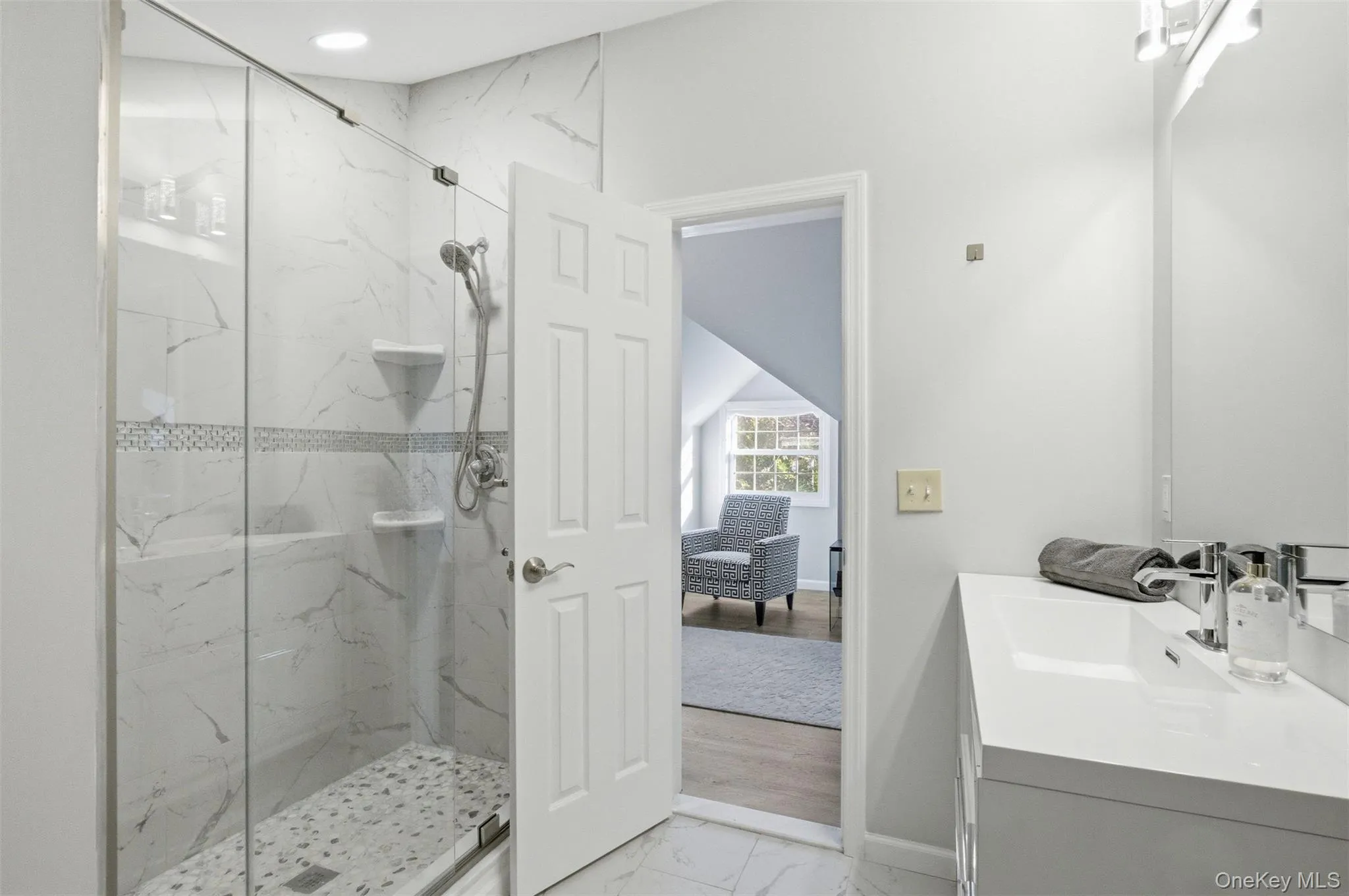 Full bath with light marble finish floors, vanity, and a marble finish shower Full bath with light marble finish floors, vanity, and a marble finish shower