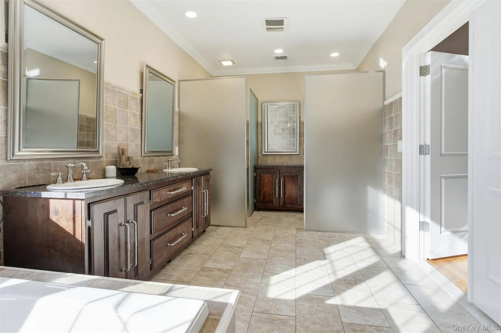Bathroom featuring double vanity, backsplash, and crown molding Bathroom featuring double vanity, backsplash, and crown molding