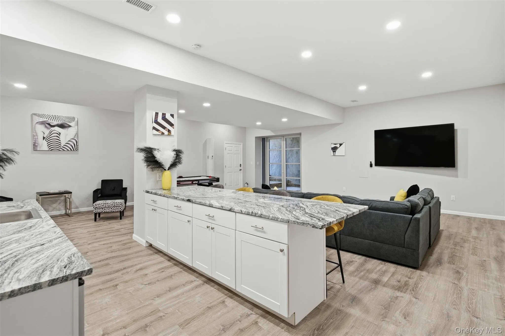 Kitchen with a kitchen breakfast bar, light stone countertops, white cabinets, open floor plan, and light wood-type flooring Kitchen with a kitchen breakfast bar, light stone countertops, white cabinets, open floor plan, and light wood-type flooring