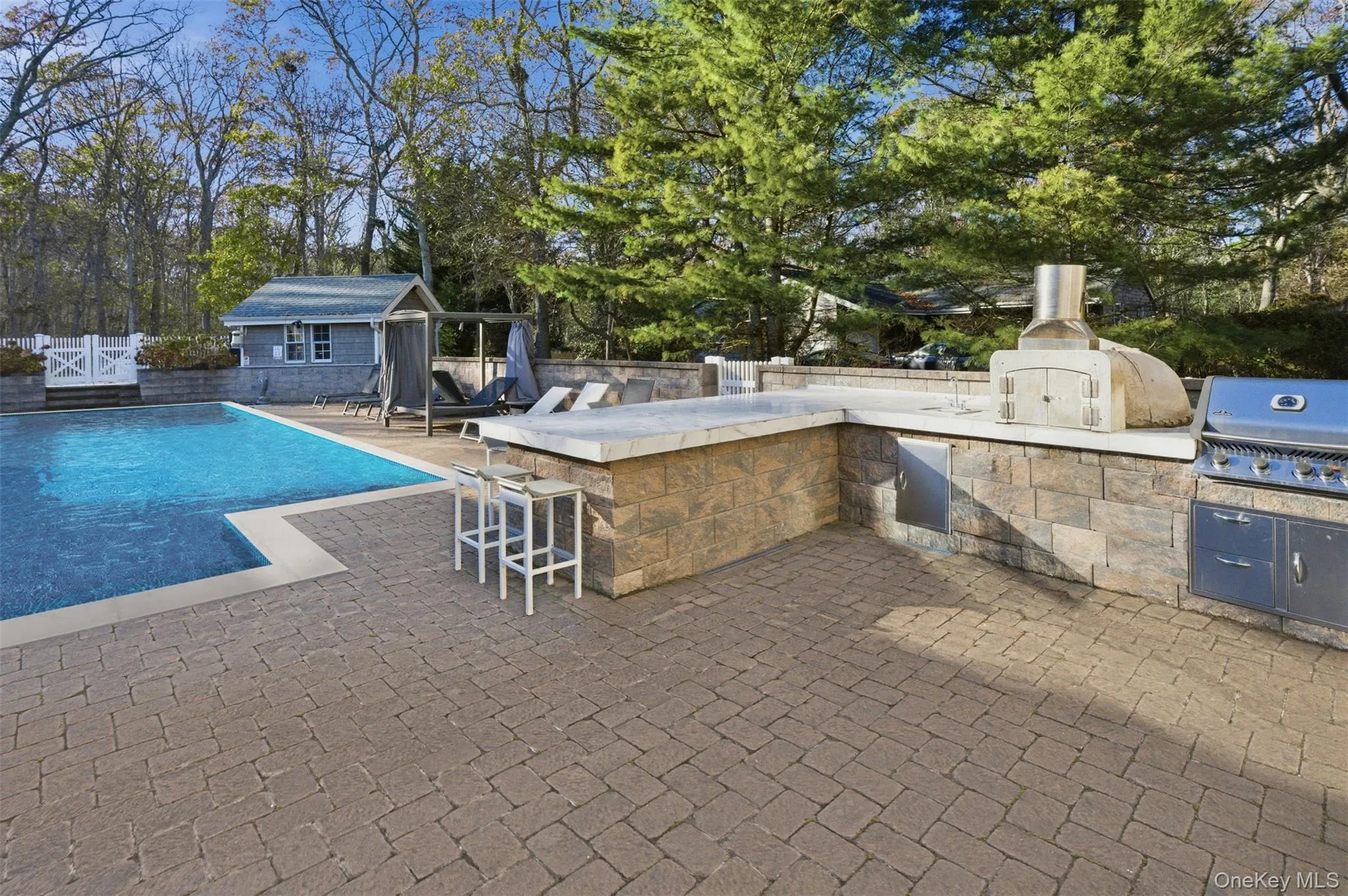 View of pool with a patio, view of wooded area, an outdoor structure, exterior bar, and area for grilling View of pool with a patio, view of wooded area, an outdoor structure, exterior bar, and area for grilling
