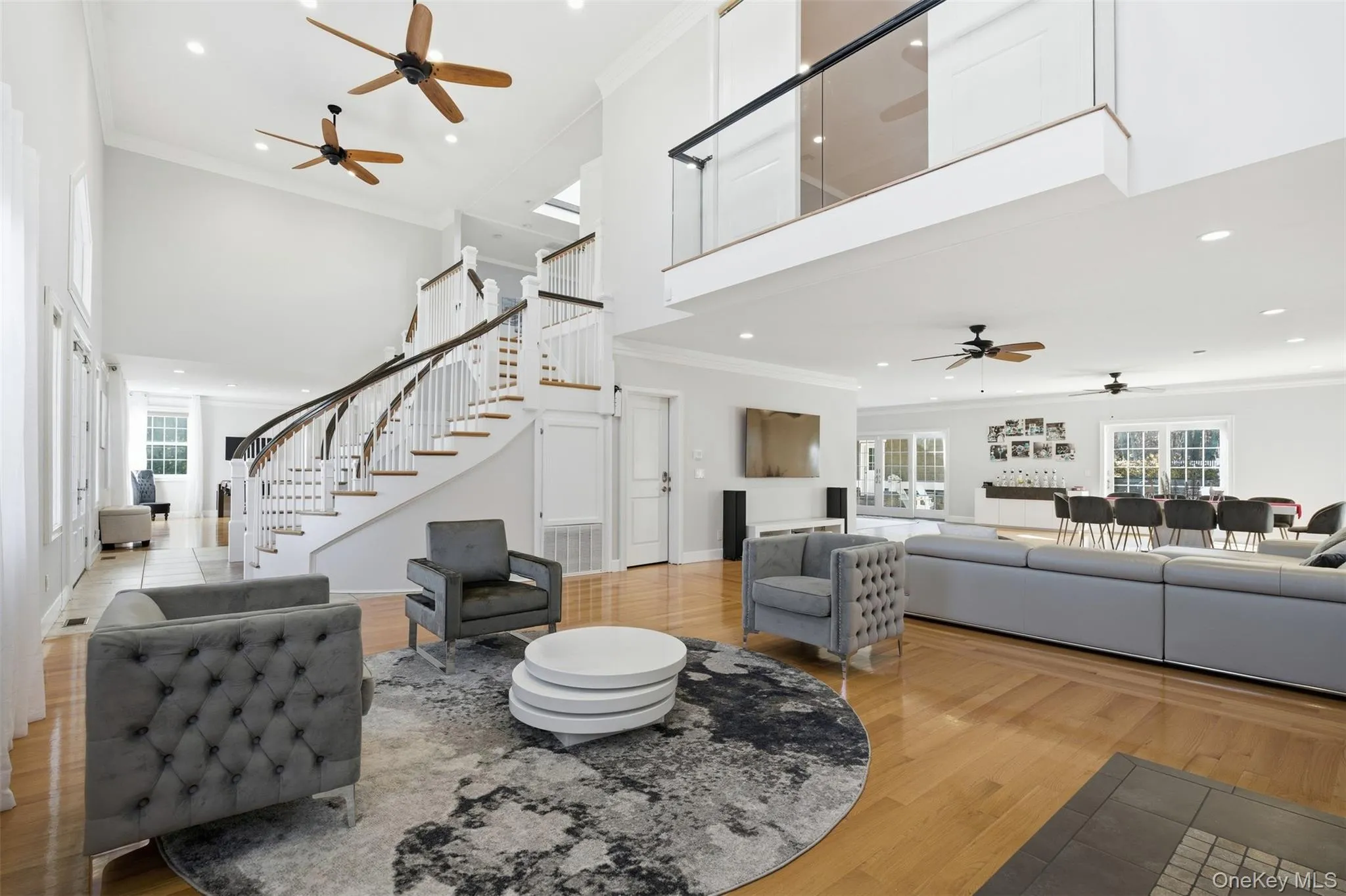Living area featuring a ceiling fan, crown molding, plenty of natural light, light wood-style floors, and stairs Living area featuring a ceiling fan, crown molding, plenty of natural light, light wood-style floors, and stairs
