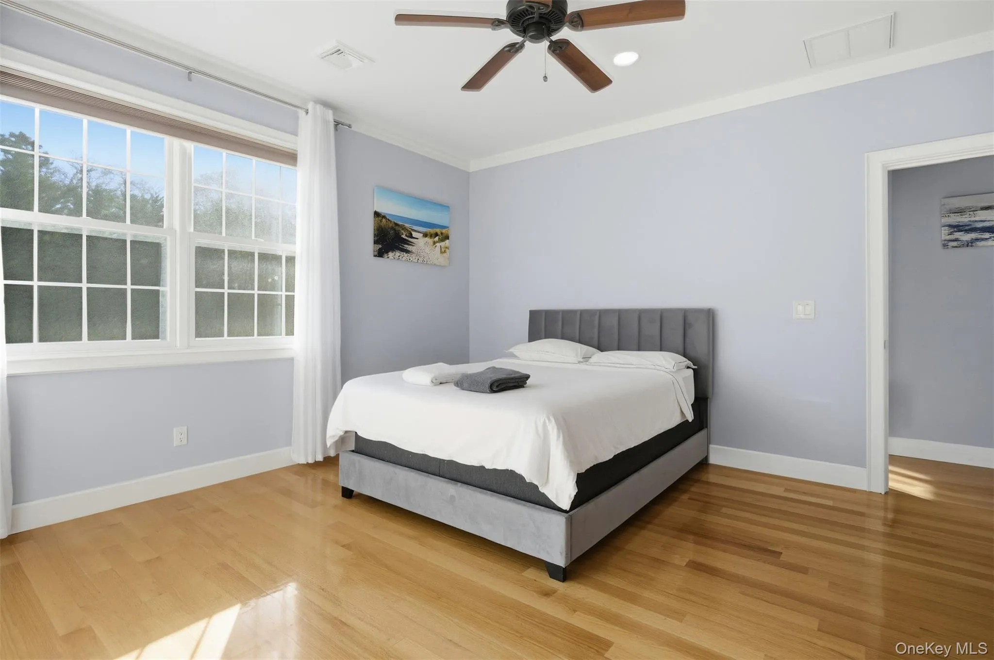 Bedroom with wood finished floors, ceiling fan, and crown molding Bedroom with wood finished floors, ceiling fan, and crown molding
