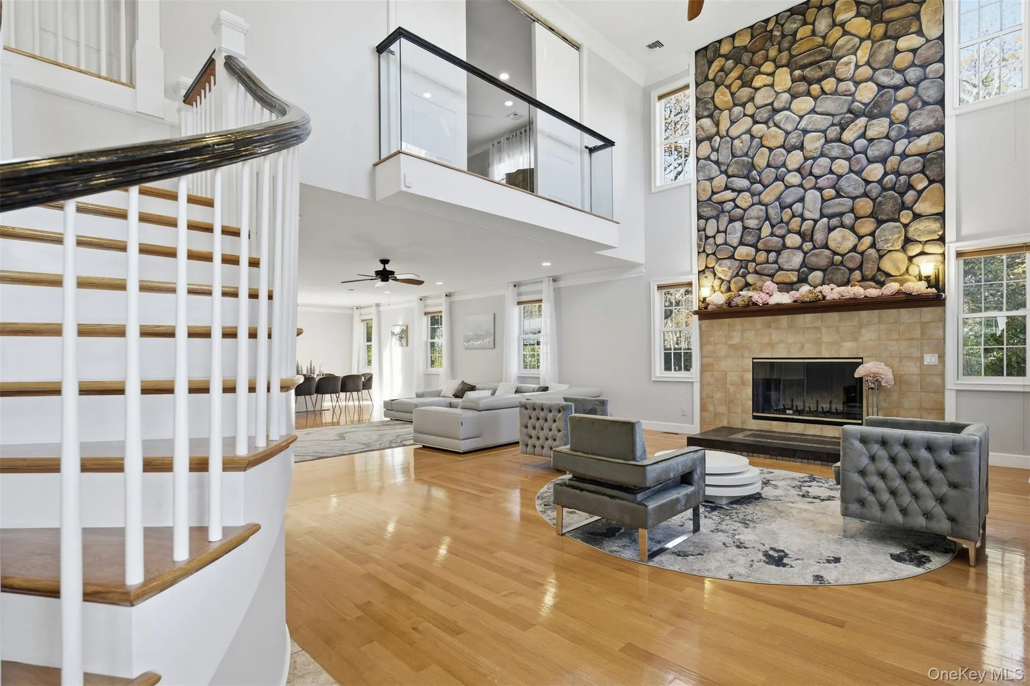 Living room with a ceiling fan, healthy amount of natural light, crown molding, a towering ceiling, and wood finished floors Living room with a ceiling fan, healthy amount of natural light, crown molding, a towering ceiling, and wood finished floors