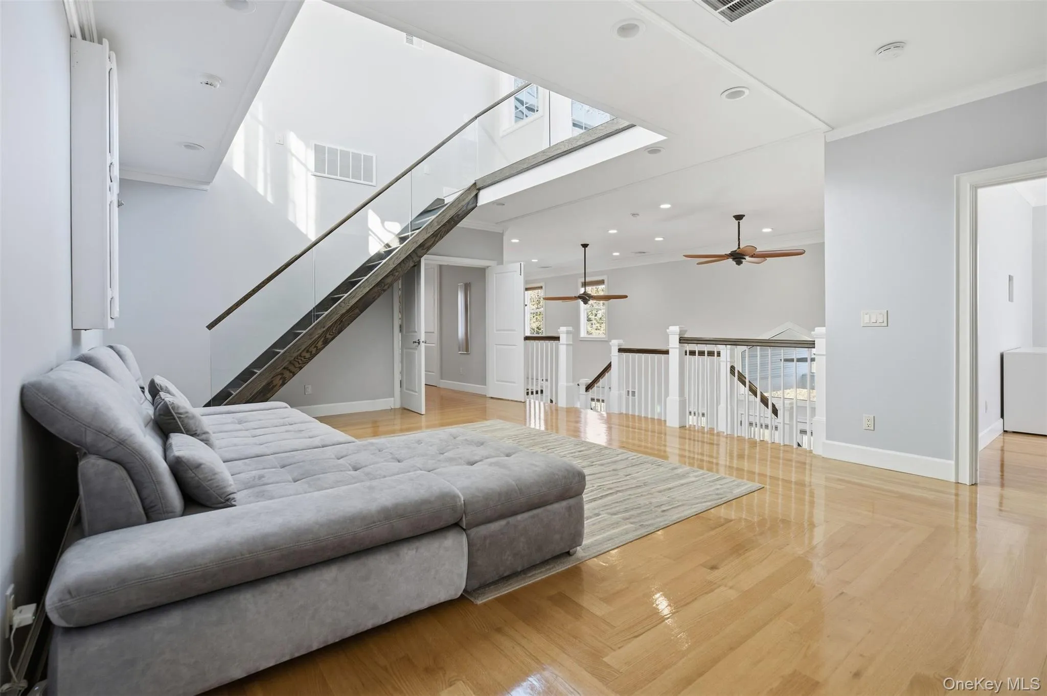 Living room featuring crown molding, recessed lighting, stairway, a skylight, and light wood-type flooring Living room featuring crown molding, recessed lighting, stairway, a skylight, and light wood-type flooring