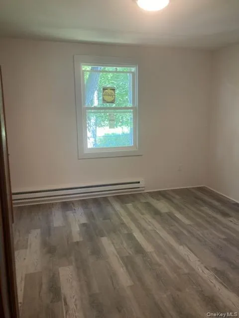 Spare room featuring baseboard heating and wood finished floors Spare room featuring baseboard heating and wood finished floors