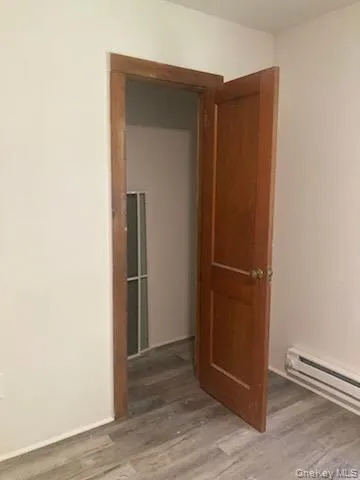 Corridor featuring a baseboard heating unit and light wood finished floors Corridor featuring a baseboard heating unit and light wood finished floors