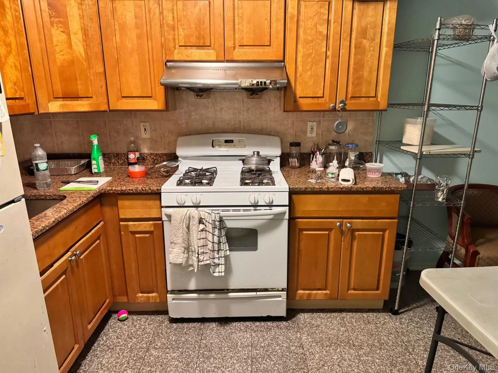 Kitchen with white appliances, brown cabinets, under cabinet range hood, and dark stone counters Kitchen with white appliances, brown cabinets, under cabinet range hood, and dark stone counters