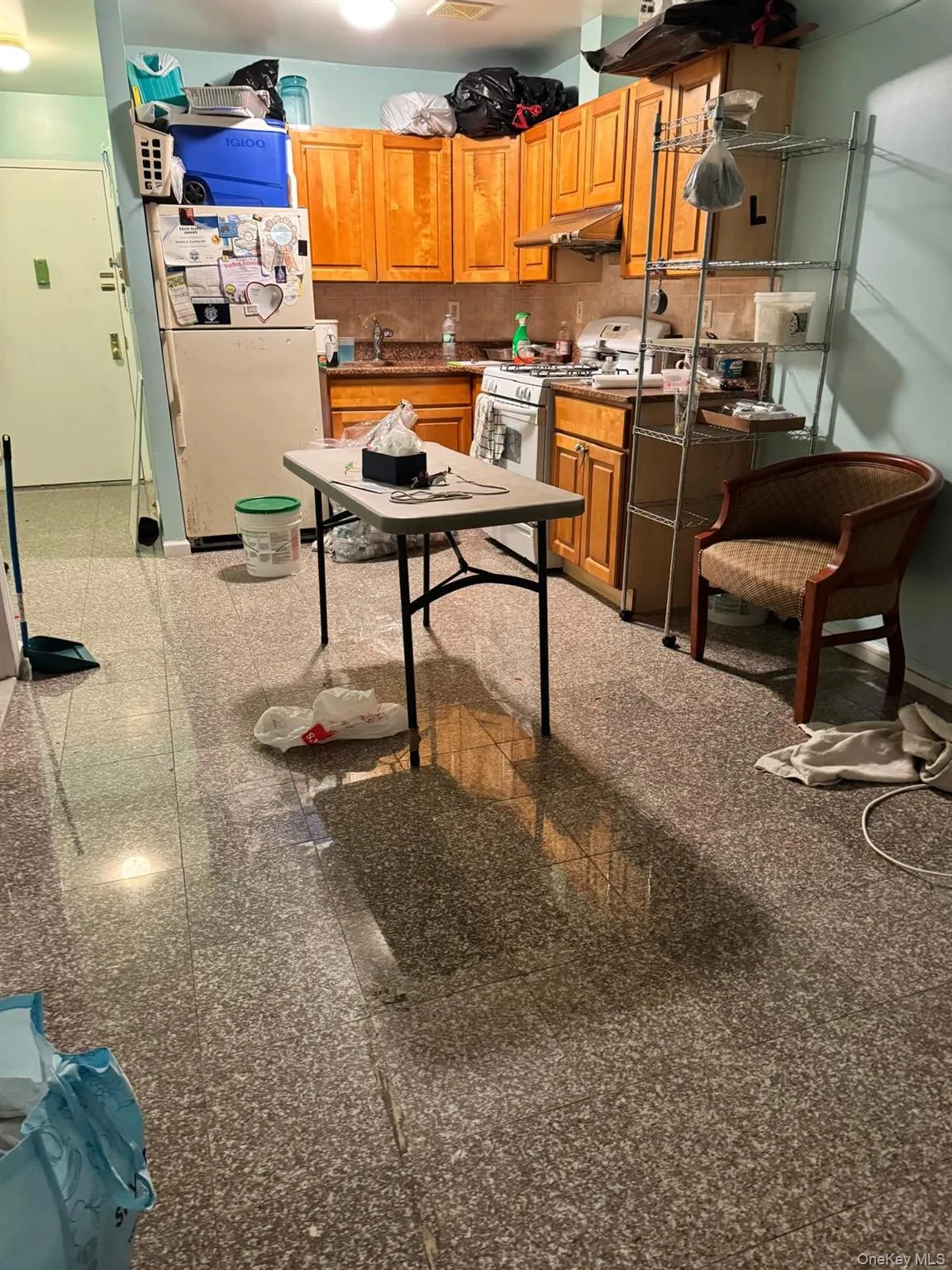 Kitchen with dark countertops, white appliances, granite floors, brown cabinets, and under cabinet range hood Kitchen with dark countertops, white appliances, granite floors, brown cabinets, and under cabinet range hood