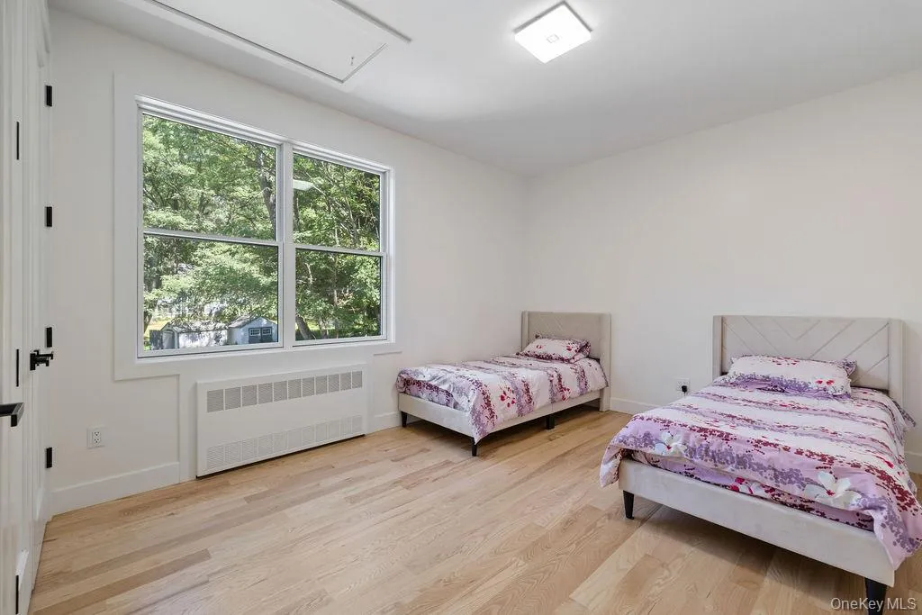 Bedroom featuring radiator, light wood finished floors, and attic access Bedroom featuring radiator, light wood finished floors, and attic access