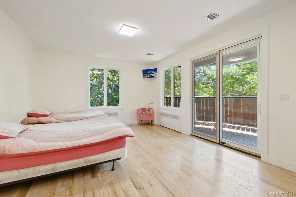 Bedroom with radiator heating unit, access to exterior, and light wood-type flooring Bedroom with radiator heating unit, access to exterior, and light wood-type flooring