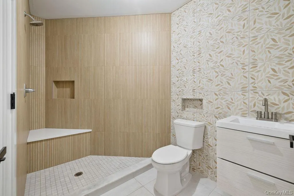 Full bath with vanity, tile patterned flooring, wallpapered walls, and tiled shower Full bath with vanity, tile patterned flooring, wallpapered walls, and tiled shower