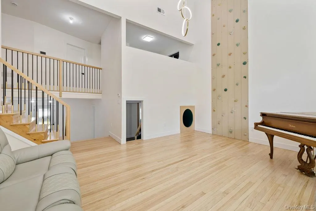 Living room with light wood-type flooring, a towering ceiling, and stairway Living room with light wood-type flooring, a towering ceiling, and stairway