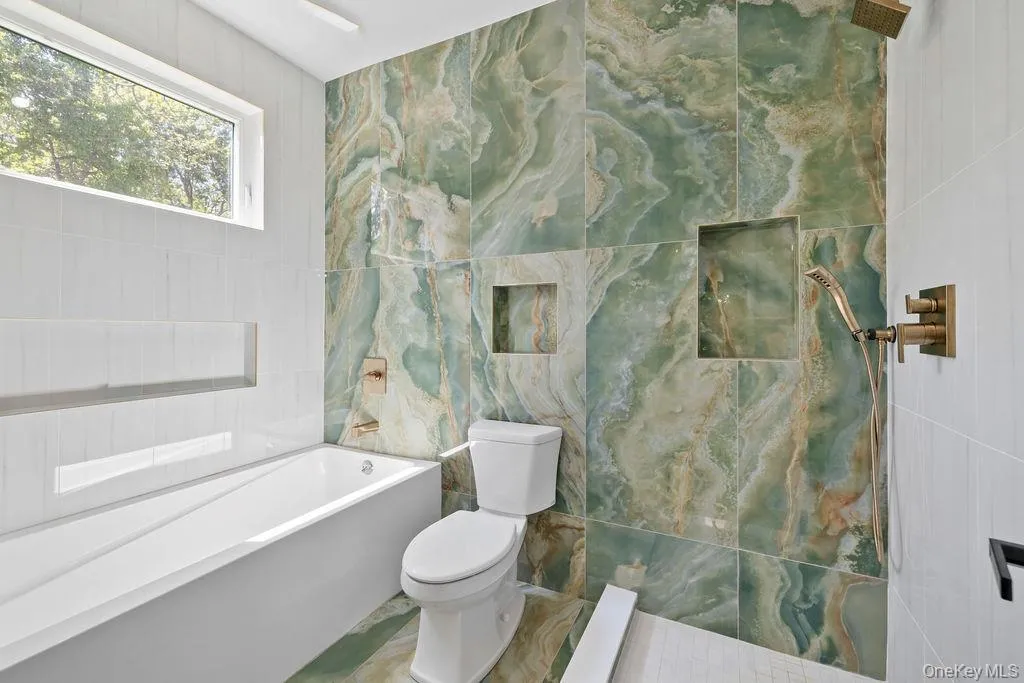 Bathroom featuring tile walls, a garden tub, and a tile shower Bathroom featuring tile walls, a garden tub, and a tile shower