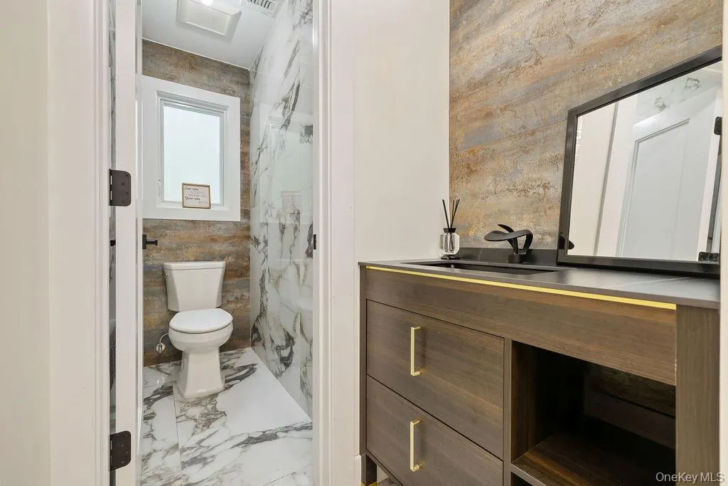 Full bath featuring vanity, a marble finish shower, light marble finish flooring, and tile walls Full bath featuring vanity, a marble finish shower, light marble finish flooring, and tile walls