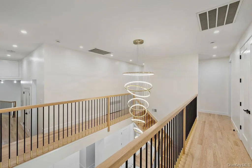 Corridor with recessed lighting, a chandelier, light wood-type flooring, and an upstairs landing Corridor with recessed lighting, a chandelier, light wood-type flooring, and an upstairs landing
