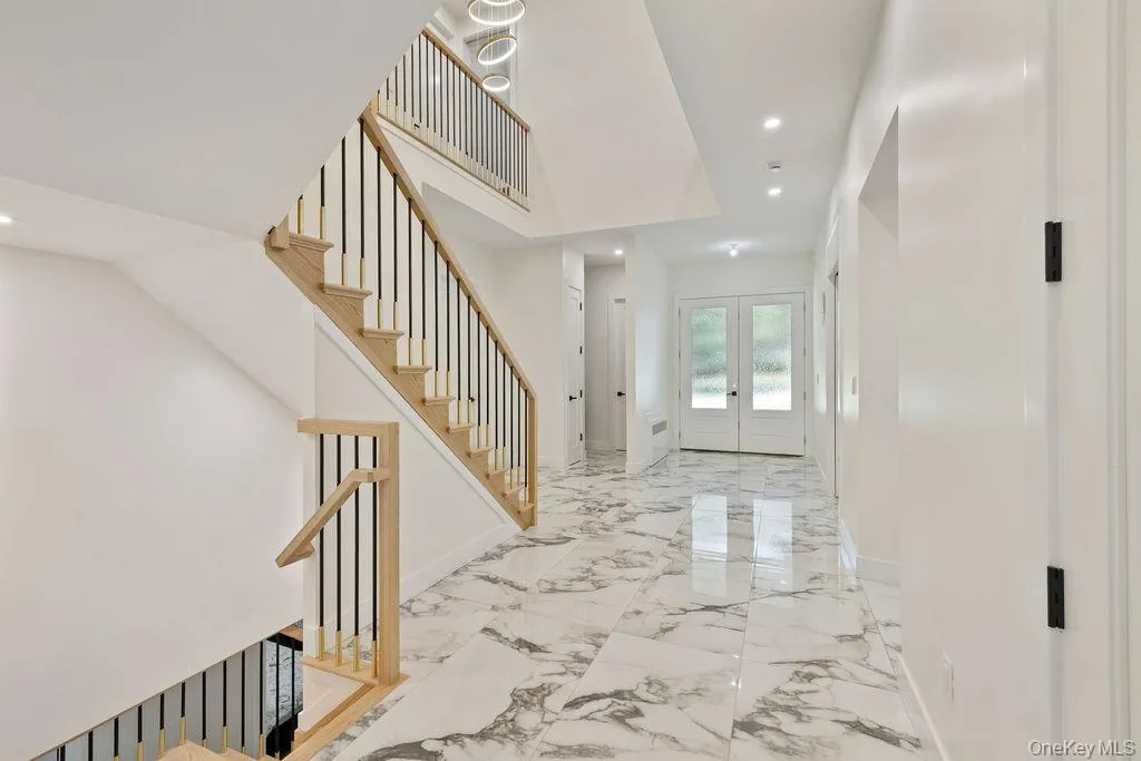 Entrance foyer with recessed lighting, stairs, french doors, and light marble finish floors Entrance foyer with recessed lighting, stairs, french doors, and light marble finish floors