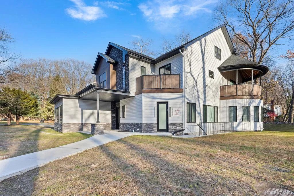 Contemporary house with a front yard, stone siding, and a balcony Contemporary house with a front yard, stone siding, and a balcony