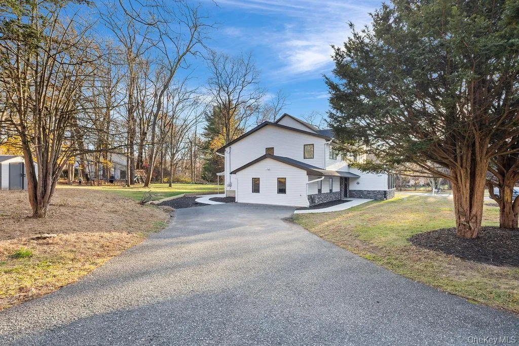 View of side of home with a lawn, asphalt driveway, and stone siding View of side of home with a lawn, asphalt driveway, and stone siding