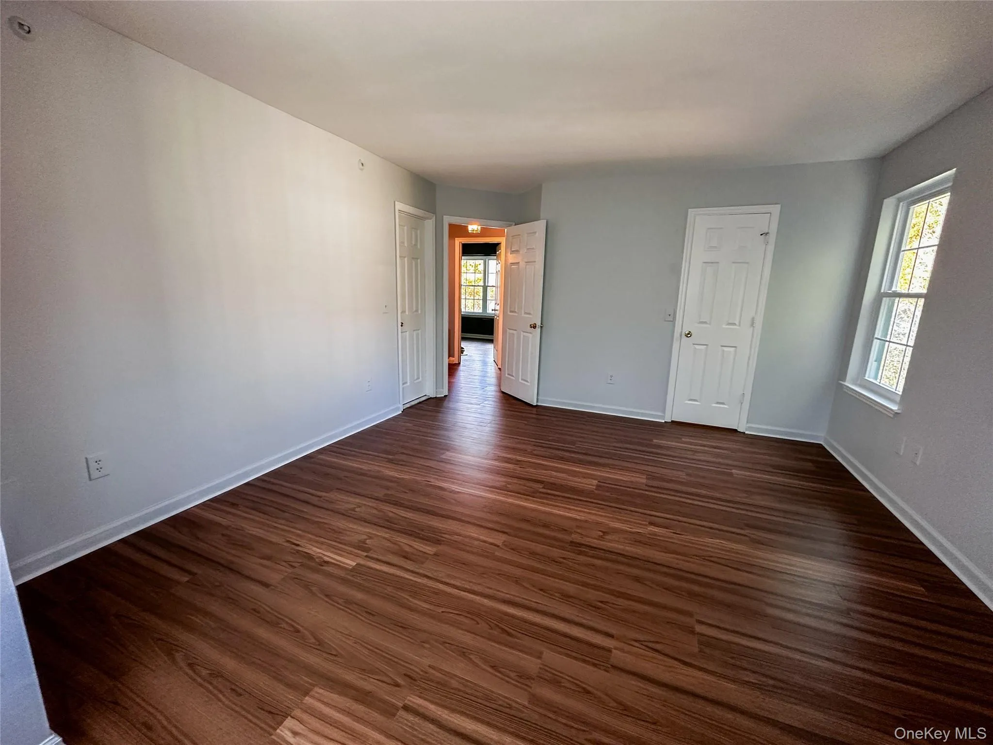 Empty room featuring dark wood-style flooring and baseboards Empty room featuring dark wood-style flooring and baseboards