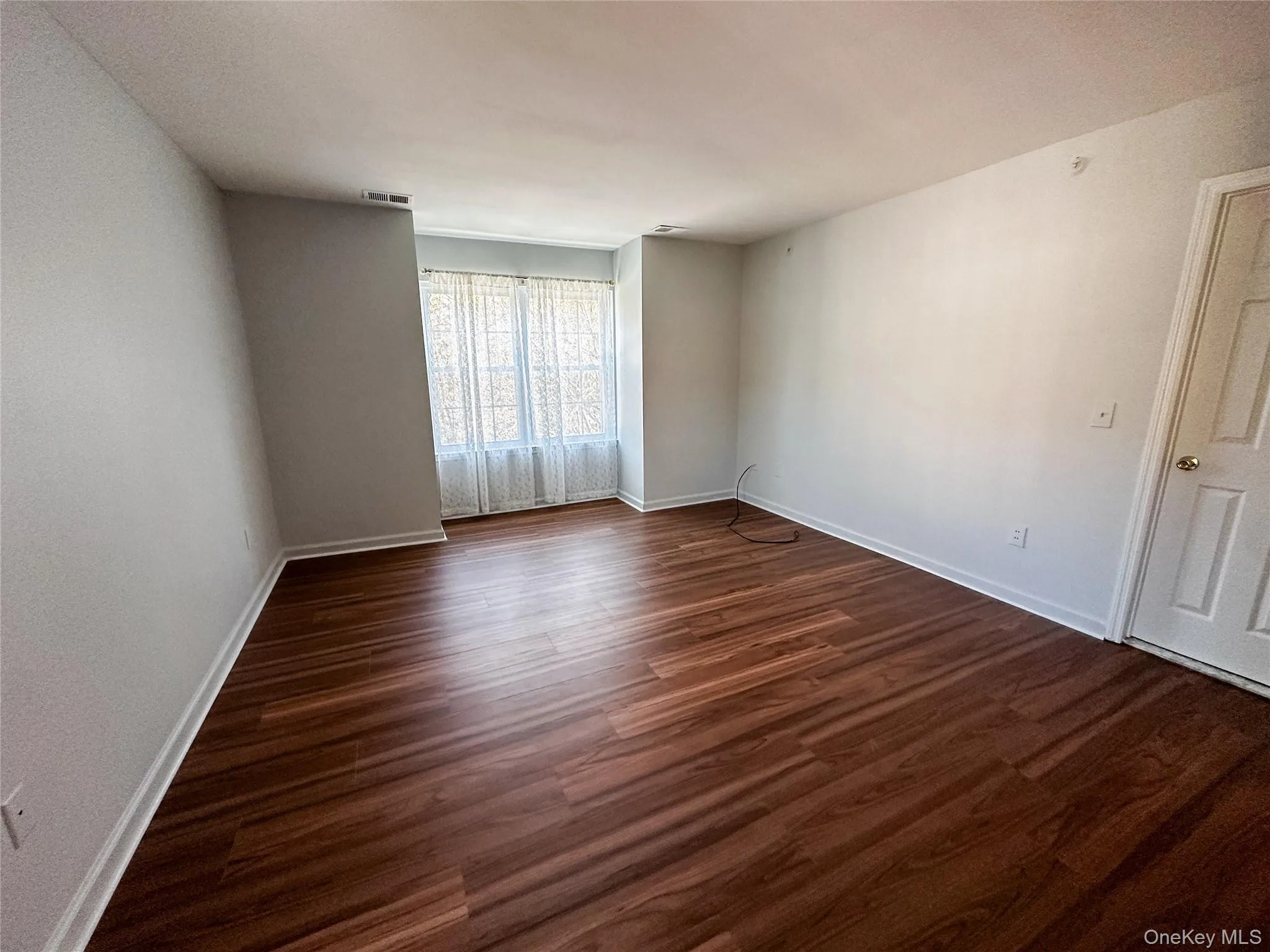 Spare room with dark wood finished floors and baseboards Spare room with dark wood finished floors and baseboards