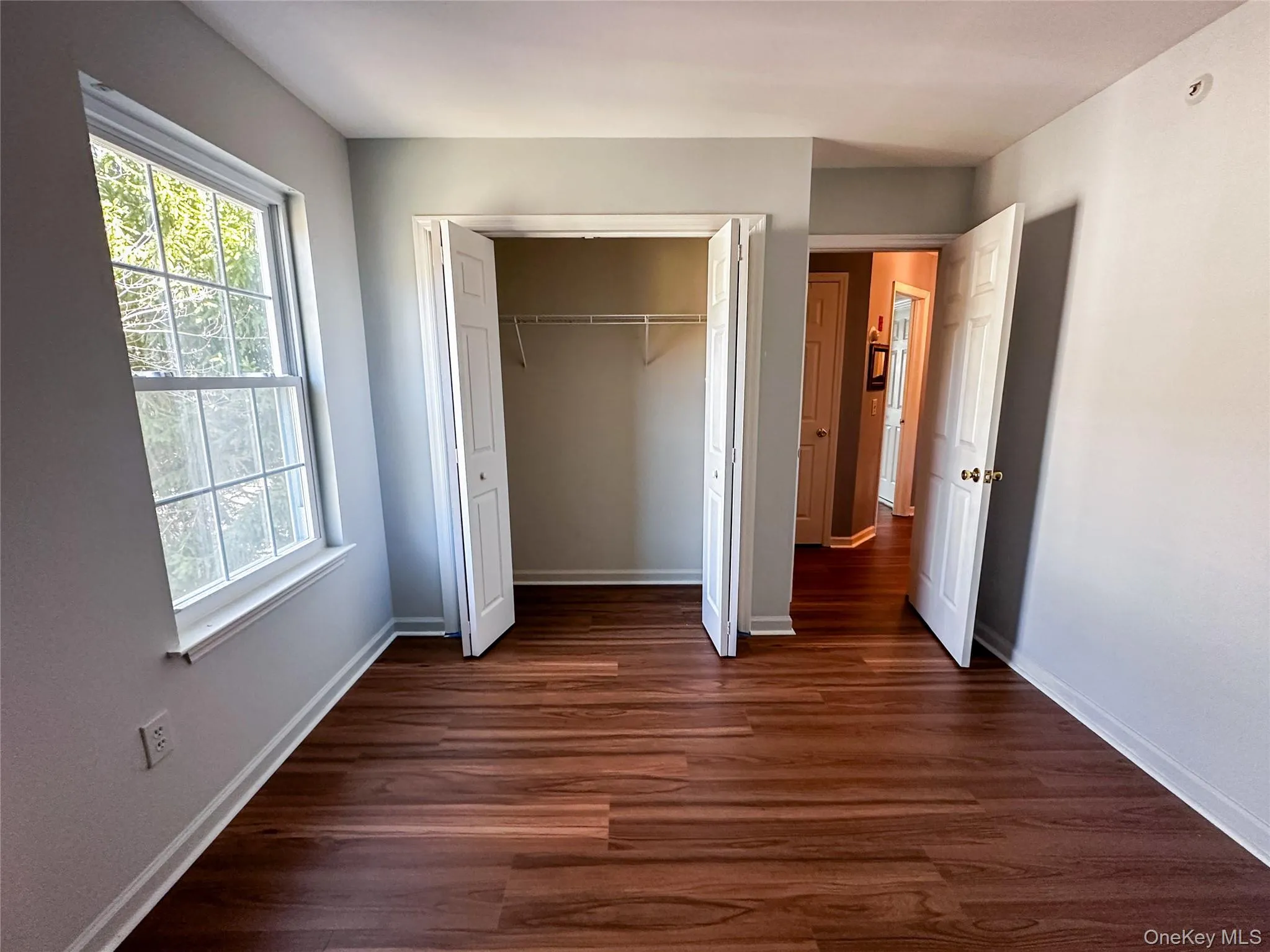 Unfurnished bedroom featuring dark wood-style flooring and a closet Unfurnished bedroom featuring dark wood-style flooring and a closet