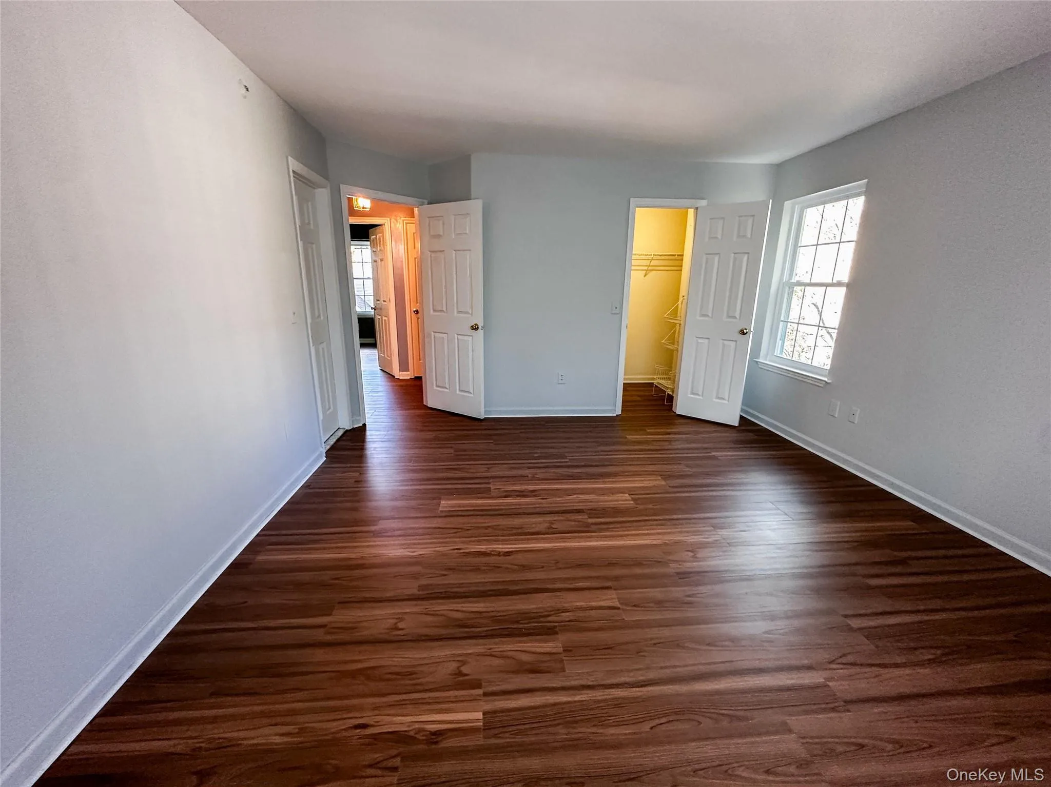 Unfurnished bedroom featuring dark wood-type flooring and a walk in closet Unfurnished bedroom featuring dark wood-type flooring and a walk in closet