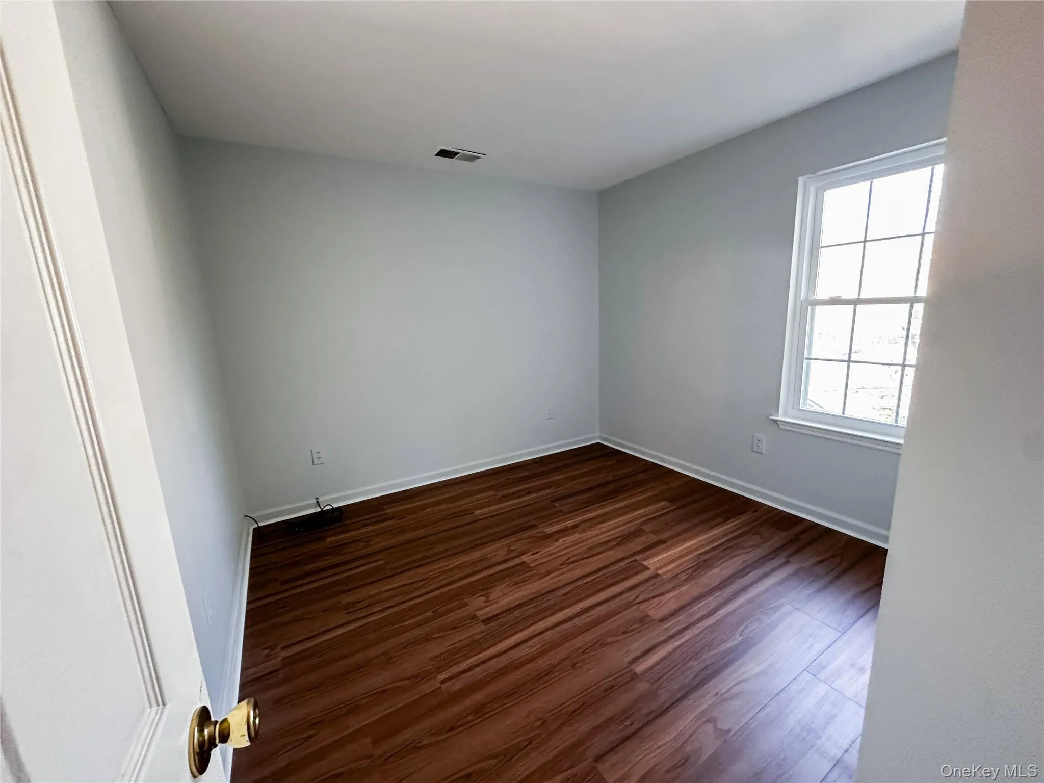 Unfurnished room with dark wood-style flooring and baseboards Unfurnished room with dark wood-style flooring and baseboards