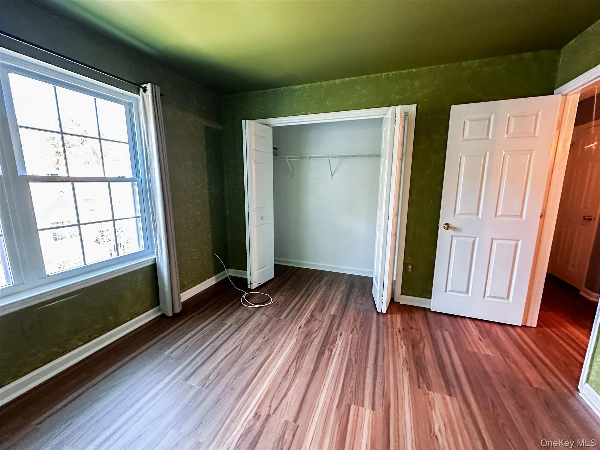 Unfurnished bedroom featuring wood finished floors and a closet Unfurnished bedroom featuring wood finished floors and a closet