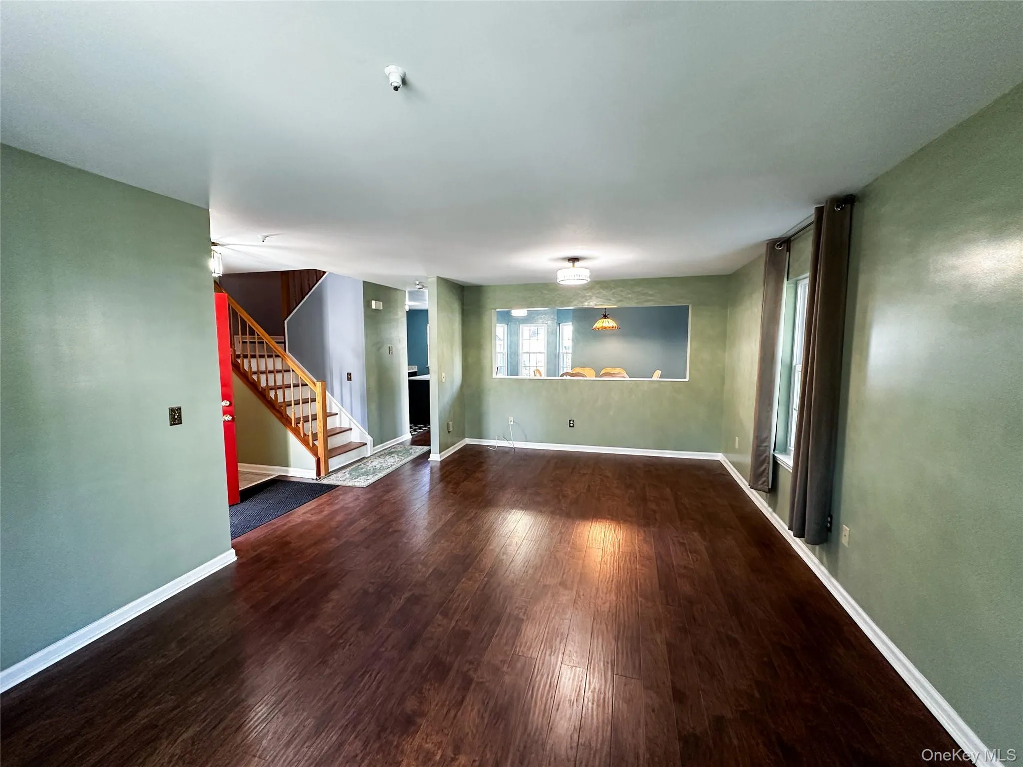 Unfurnished living room featuring stairway and wood-type flooring Unfurnished living room featuring stairway and wood-type flooring