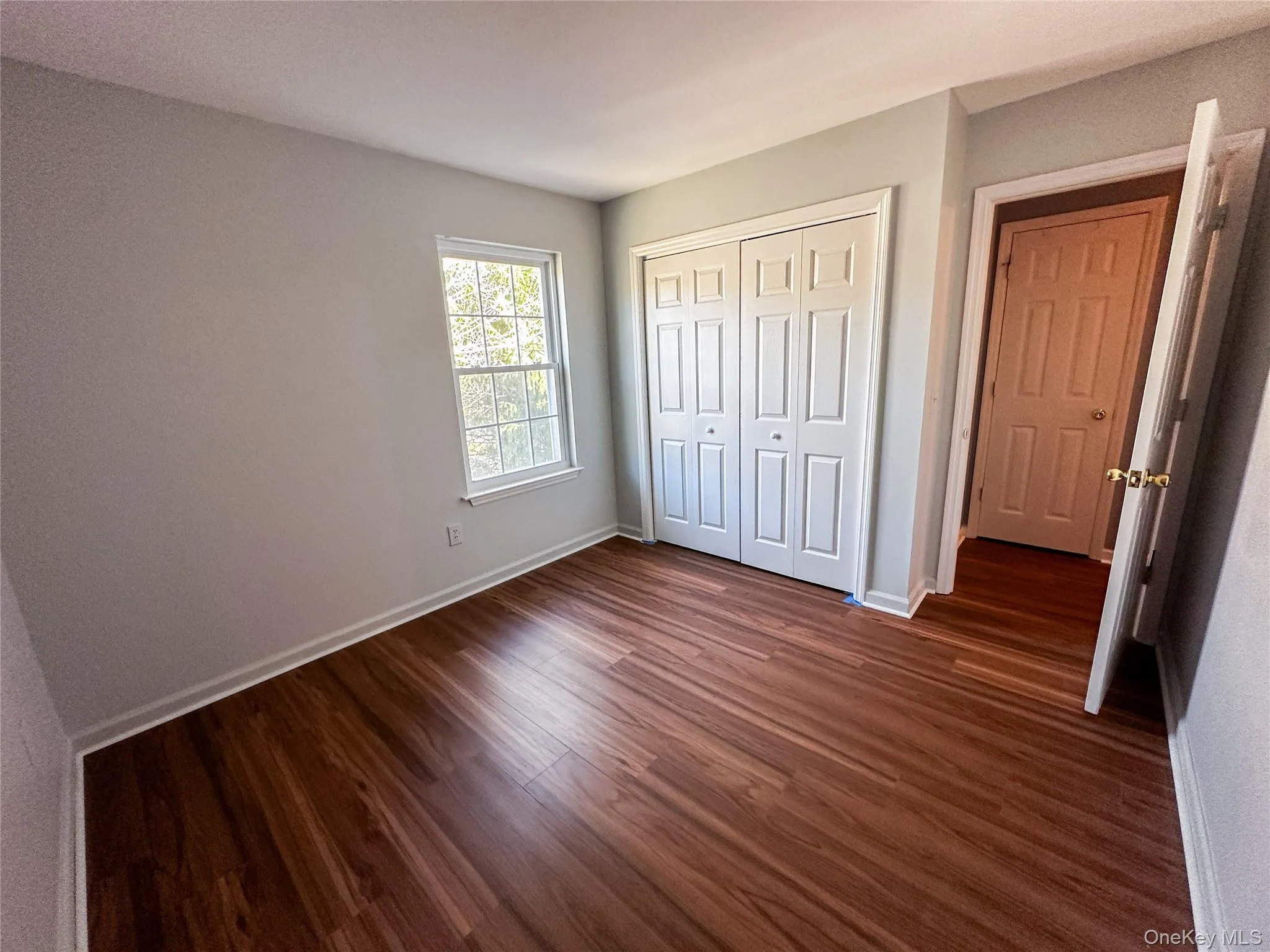 Unfurnished bedroom featuring dark wood-type flooring and a closet Unfurnished bedroom featuring dark wood-type flooring and a closet