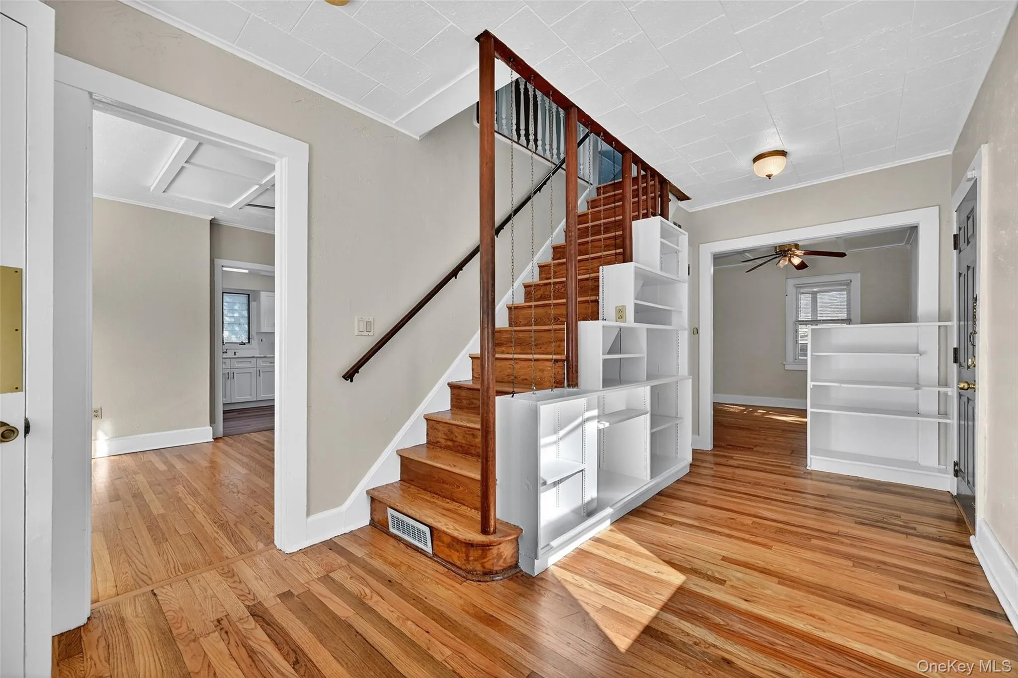 Stairway with hardwood / wood-style floors, ceiling fan, and ornamental molding Stairway with hardwood / wood-style floors, ceiling fan, and ornamental molding