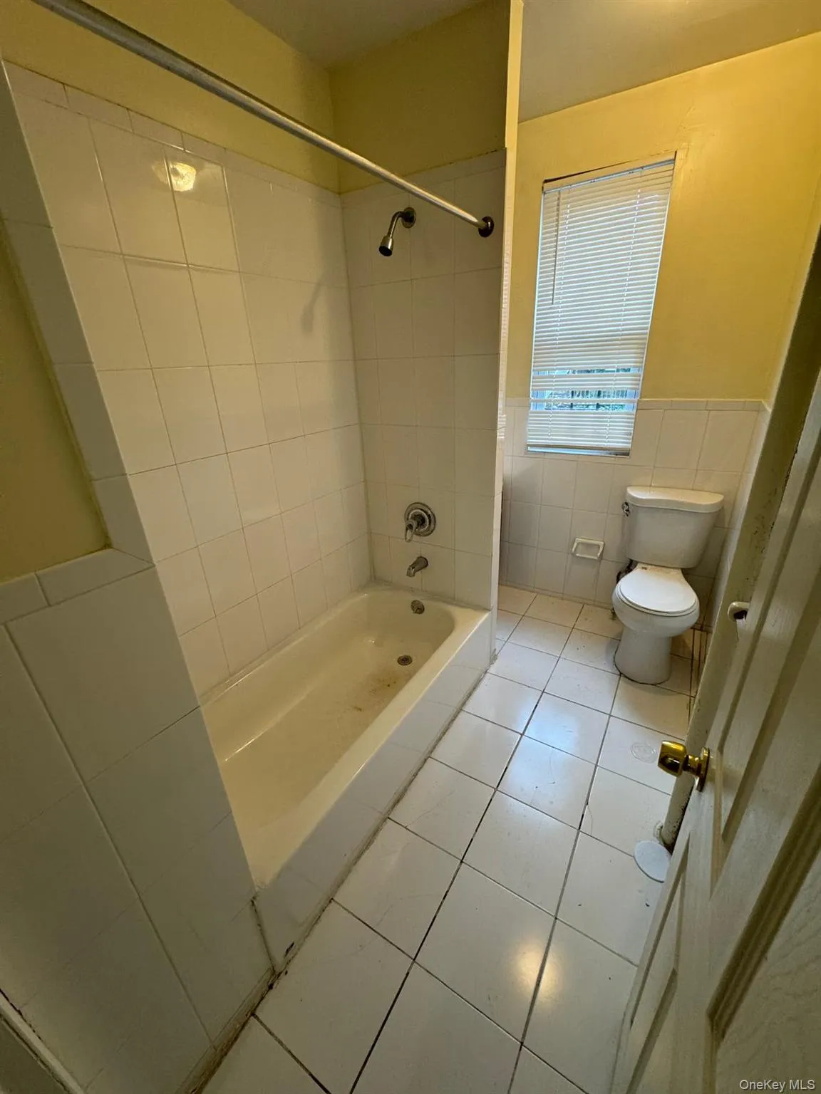 Full bath with tile patterned flooring, bathing tub / shower combination, tile walls, and wainscoting Full bath with tile patterned flooring, bathing tub / shower combination, tile walls, and wainscoting