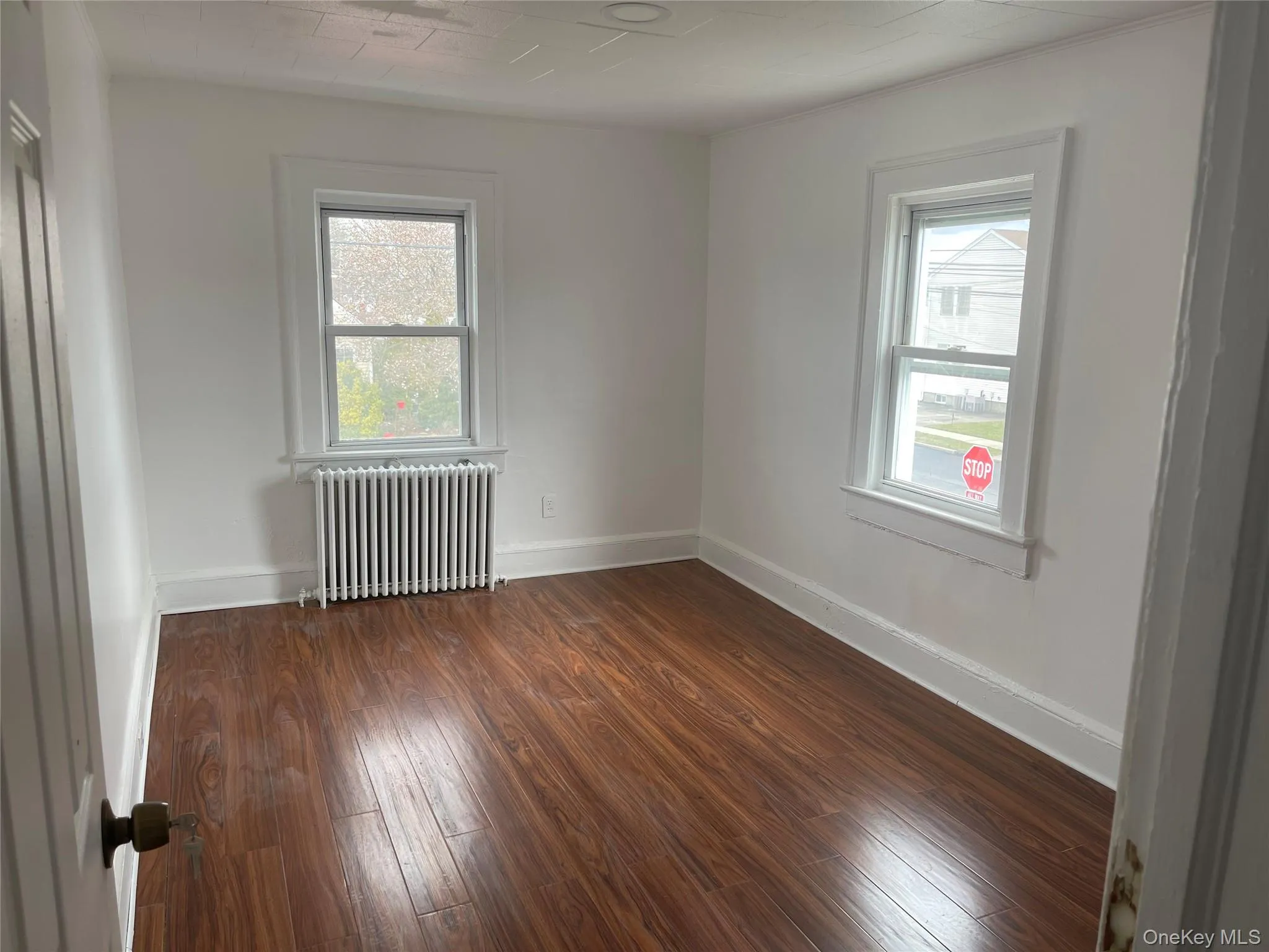 Empty room featuring radiator and dark wood-type flooring Empty room featuring radiator and dark wood-type flooring