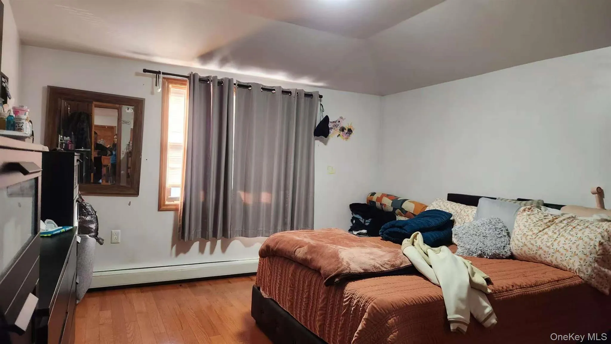 Bedroom featuring baseboard heating, wood finished floors, and lofted ceiling Bedroom featuring baseboard heating, wood finished floors, and lofted ceiling