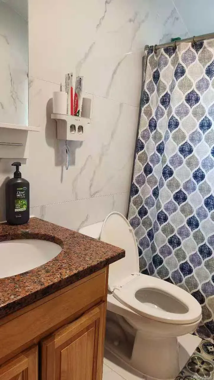 Full bathroom featuring a shower with curtain, vanity, and tile walls Full bathroom featuring a shower with curtain, vanity, and tile walls