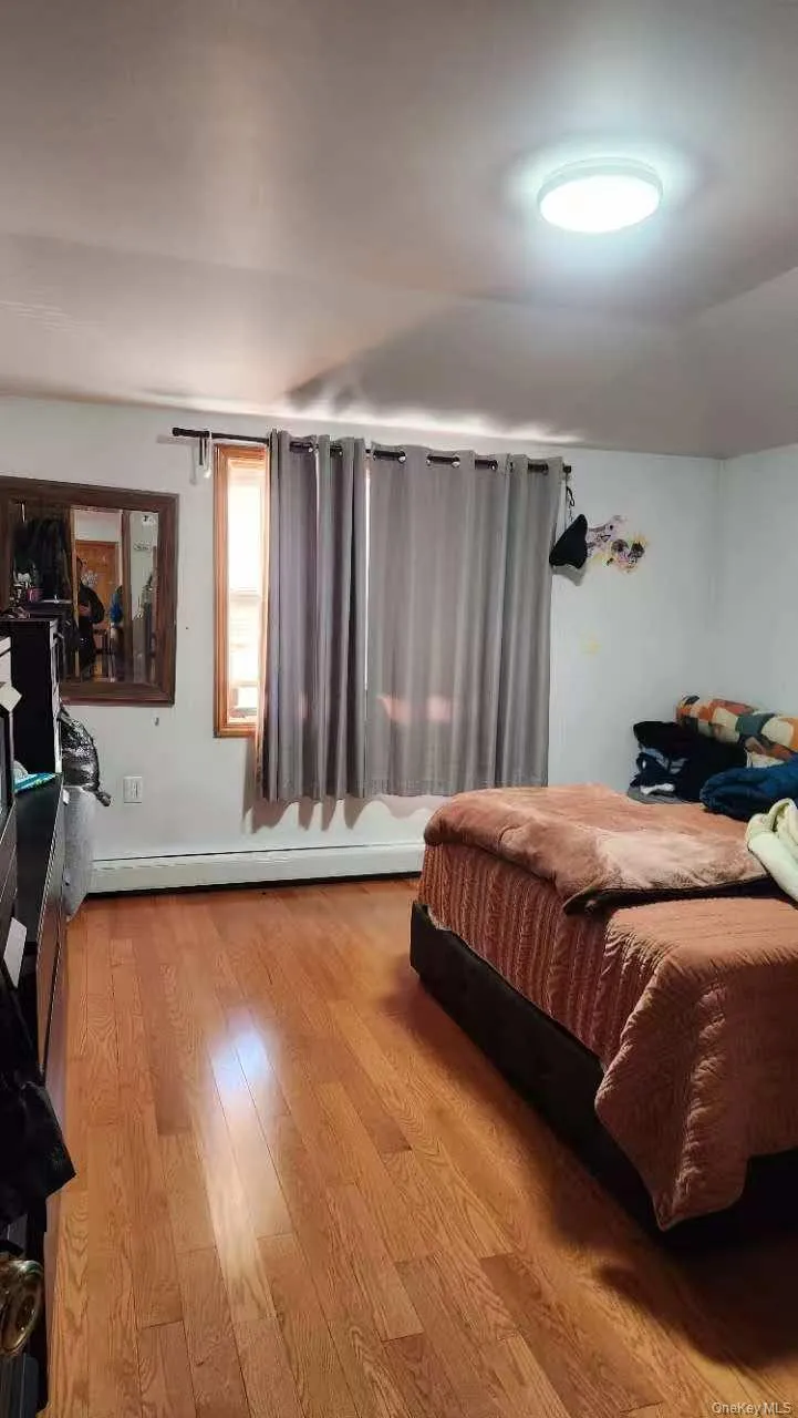 Bedroom featuring wood finished floors and baseboard heating Bedroom featuring wood finished floors and baseboard heating