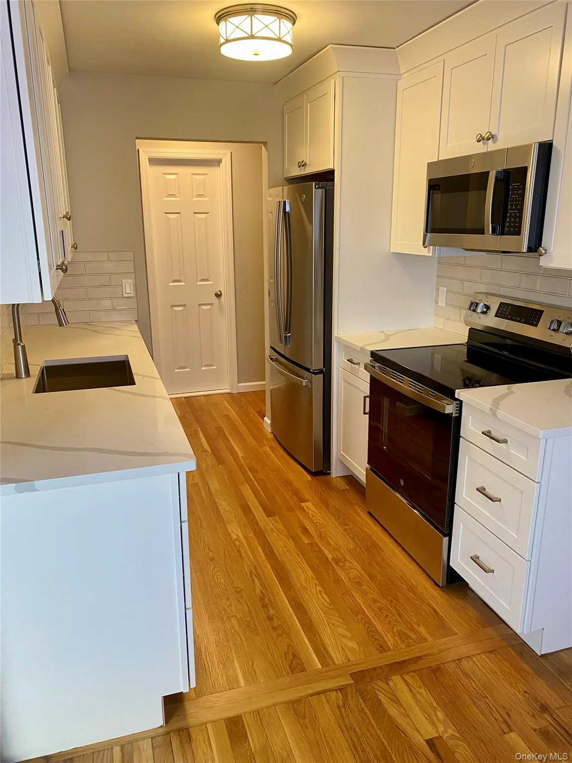 Kitchen featuring appliances with stainless steel finishes, decorative backsplash, and white cabinets Kitchen featuring appliances with stainless steel finishes, decorative backsplash, and white cabinets